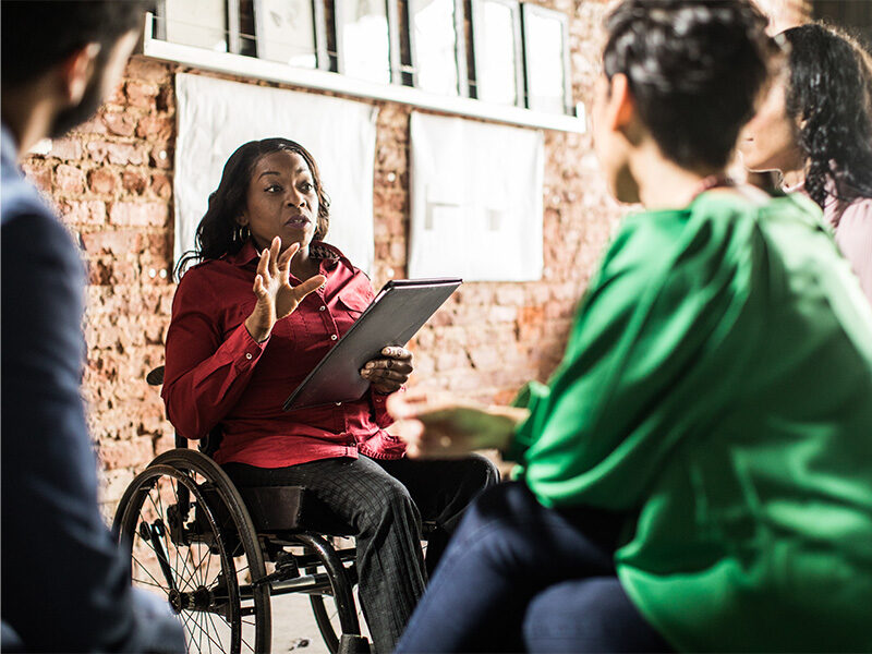 Businesswoman in wheelchair leading group discussion in creative office