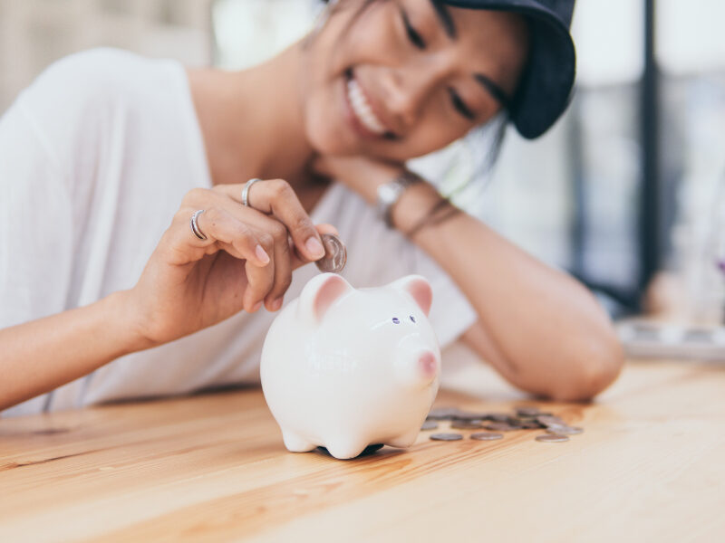Woman putting a coin in the piggy bank